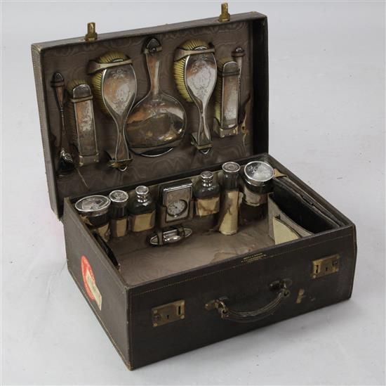 A George V leather travelling toilet case containing fifteen silver mounted accoutrements, 20in.